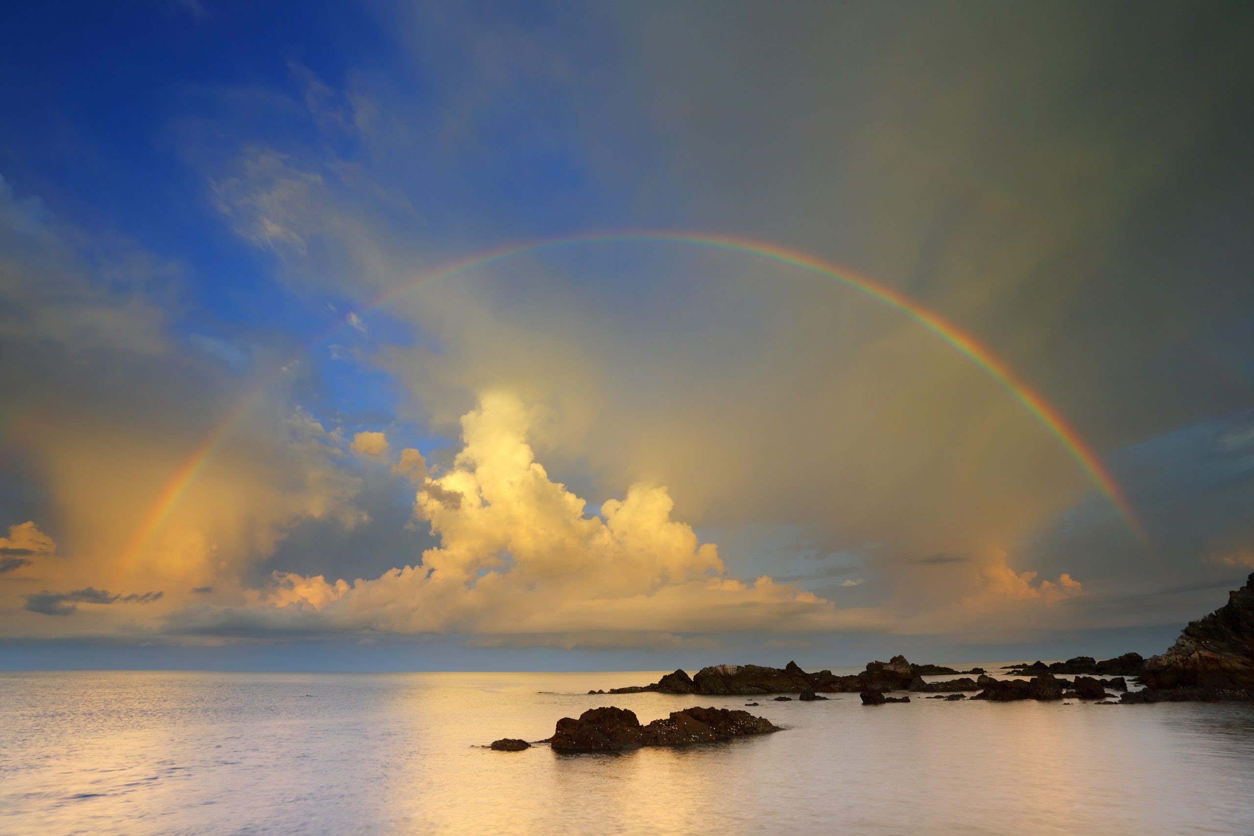 Rainbow with clouds over a water body
